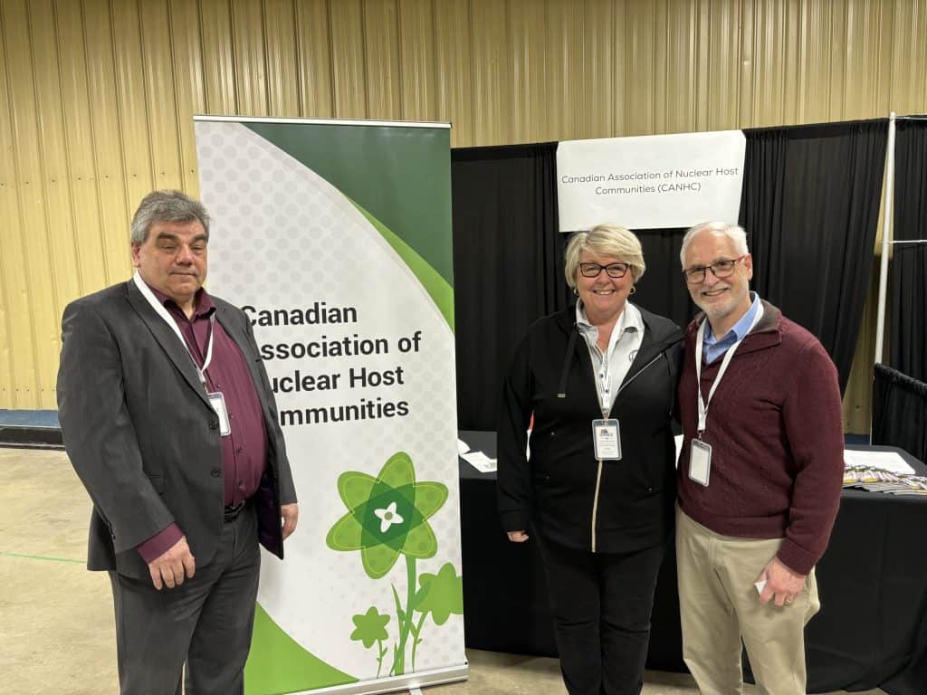 Group photo of three professionals at the ARMA conference, showcasing networking and collaboration in nuclear and radioactive waste management, with ARMA branding in the background.